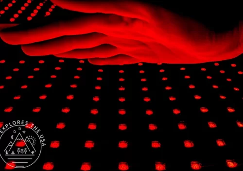 Astarexin Red Light Therapy Pad turned on with a hand over it lit up in red