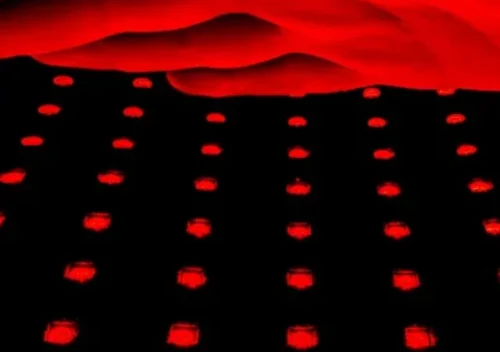 Astarexin Red Light Therapy Pad turned on with a hand over it lit up in red