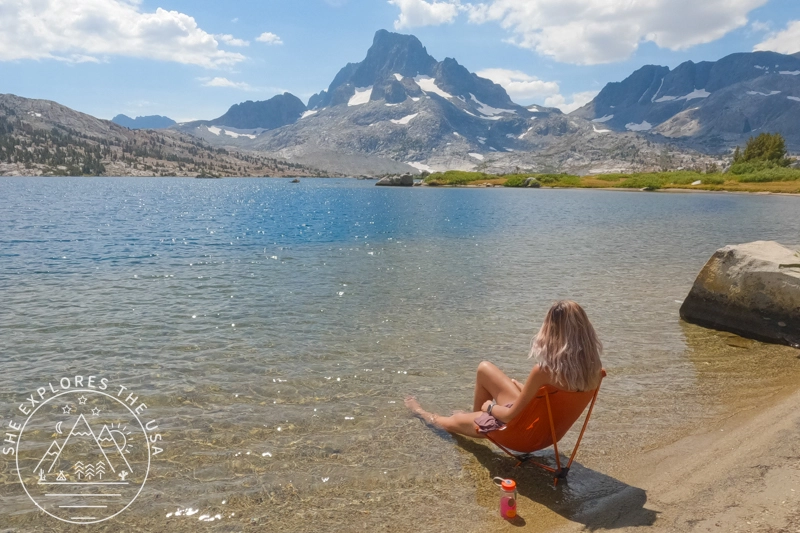 Patagonia Summer Sale 2025 - a female hiker sits in her REI flexlite air chair in thousand island lake in the Sierra