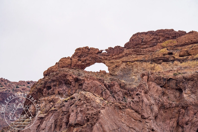 Two natural rock arches in the red volcanic rock formations along Arch Canyon at Organ Pipe Cactus National Monument, viewed from the parking area pullout.