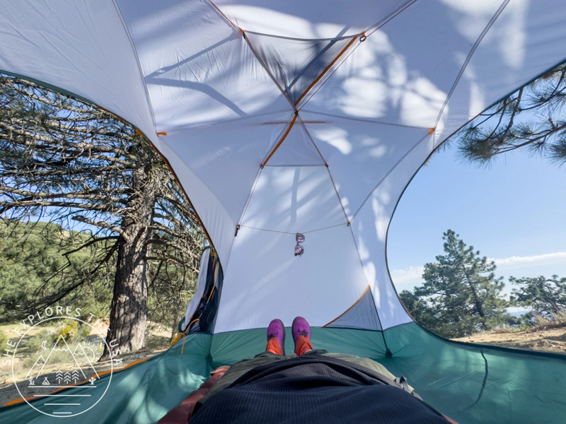 mountain hardwear mineral king all season tent seen from inside with sunglasses hanging from the HangTight™ System rope, both side doors wide open showing nature outside, and the photographer laying down on the tent floor in the foreground
