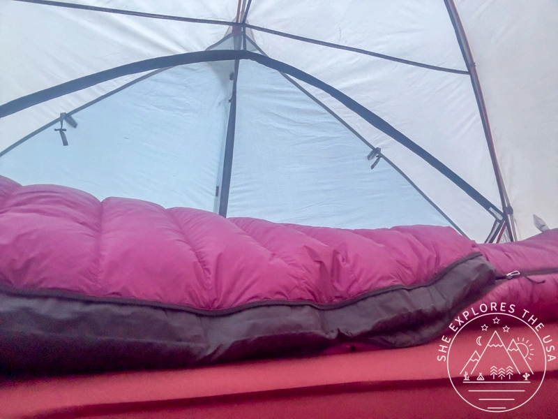 Feathered Friends Petrel 10 UL sleeping bag laying on a mattress inside a tent, with a woman inside