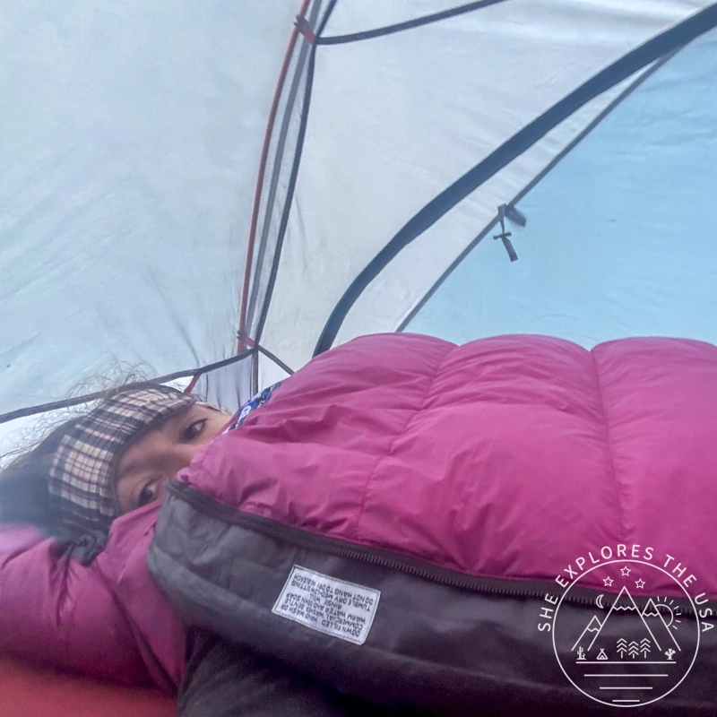 Feathered Friends Petrel 10 UL sleeping bag laying on a mattress inside a tent, with a woman inside