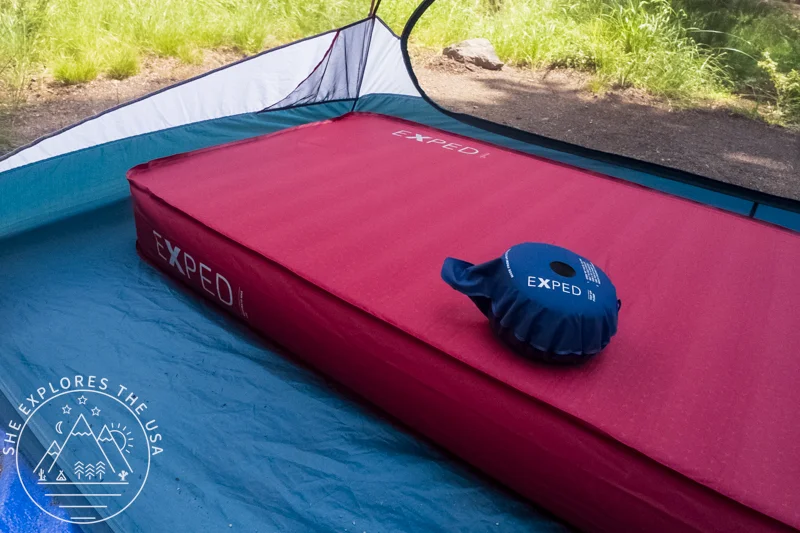 Exped MegaMat Max Sleeping Pad inflated in a tent, with its manual pump on top