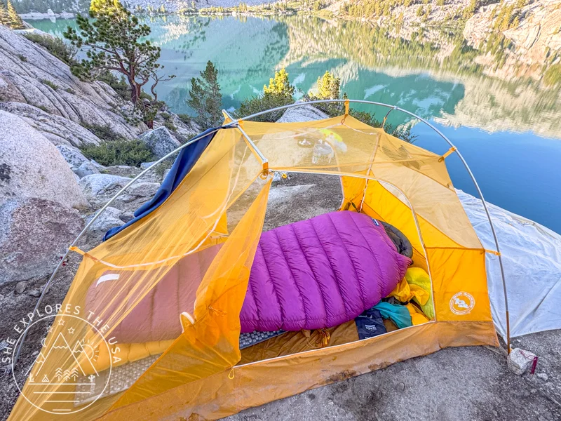Feathered Friends Petrel UL 10 Sleeping Bag in a yellow tent by a lake