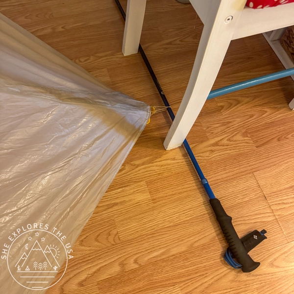 Improvised indoor setup using trekking poles and a chair to pitch a tent rainfly